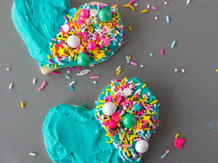 Two Heart Cookies with Blue Frosting are decorated with sprinkles on half of the cookie.
