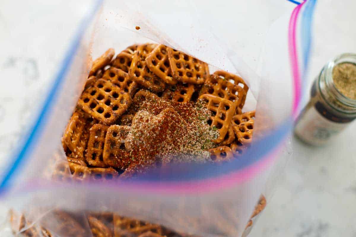 The seasonings have been sprinkled over the pretzels in the plastic bag.