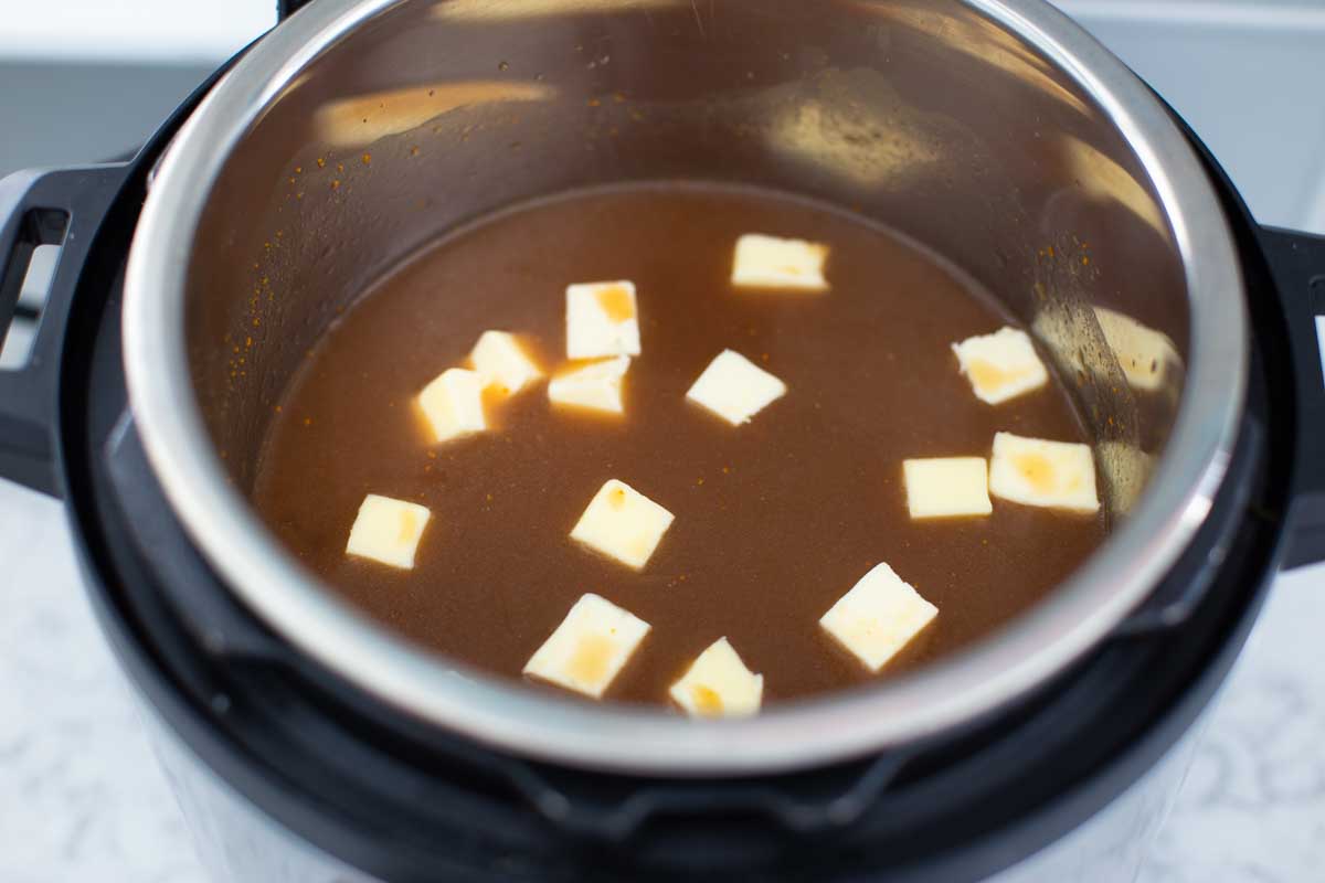 The beef broth and cubed butter have been added to the Instant Pot.