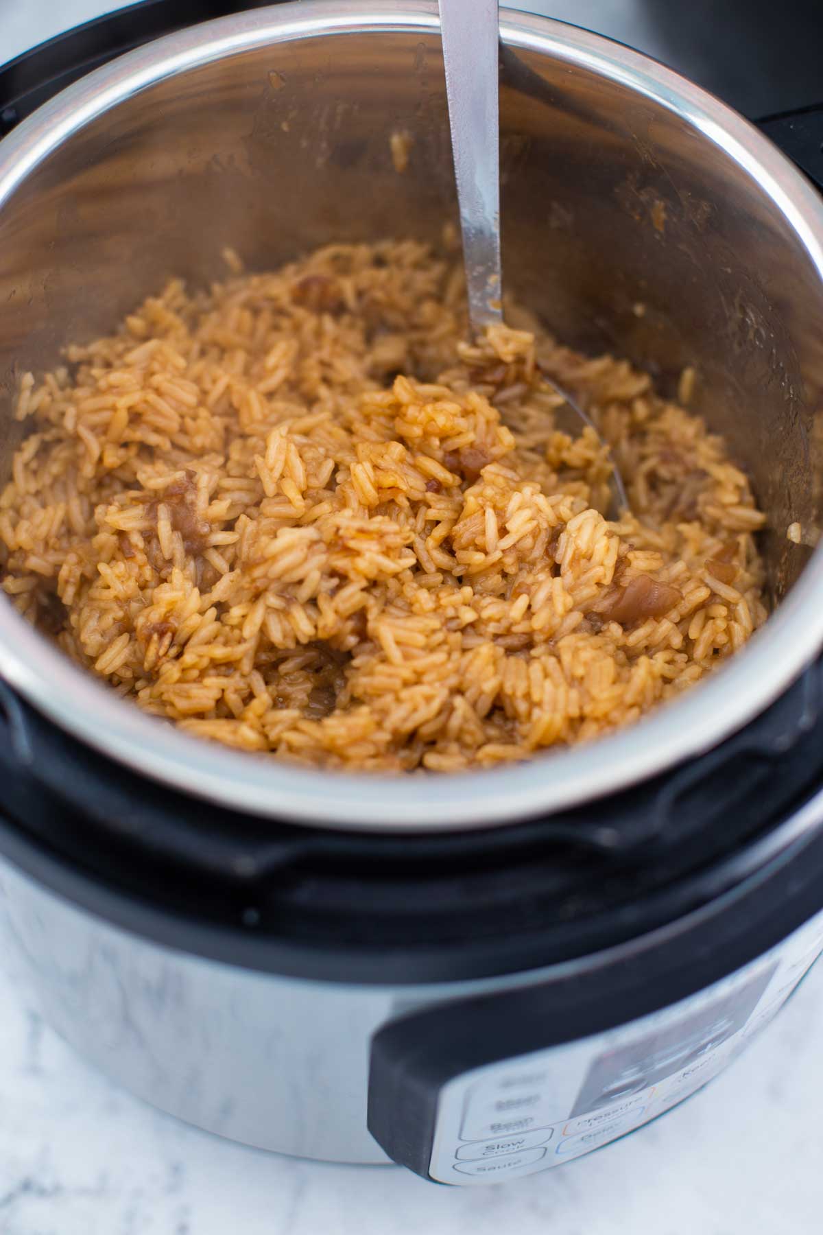 The finished sticky butter rice is shown being fluffed with a spoon inside the Instant Pot.