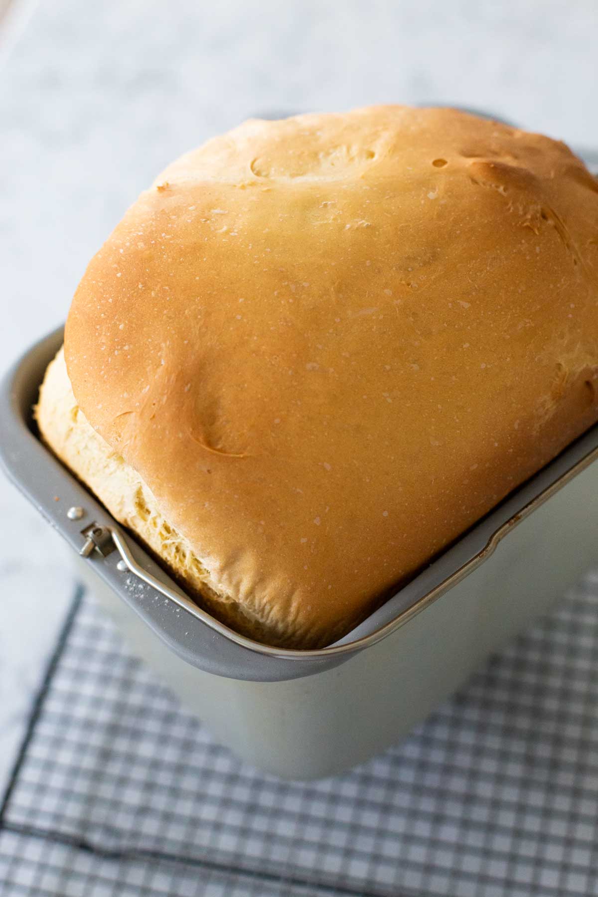 The finished challah loaf is cooling in the bread machine pan.