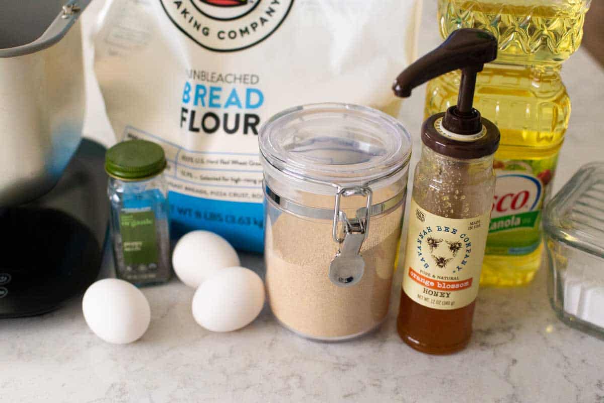 The ingredients to make the challah bread are on the counter next to the bread machine pan.