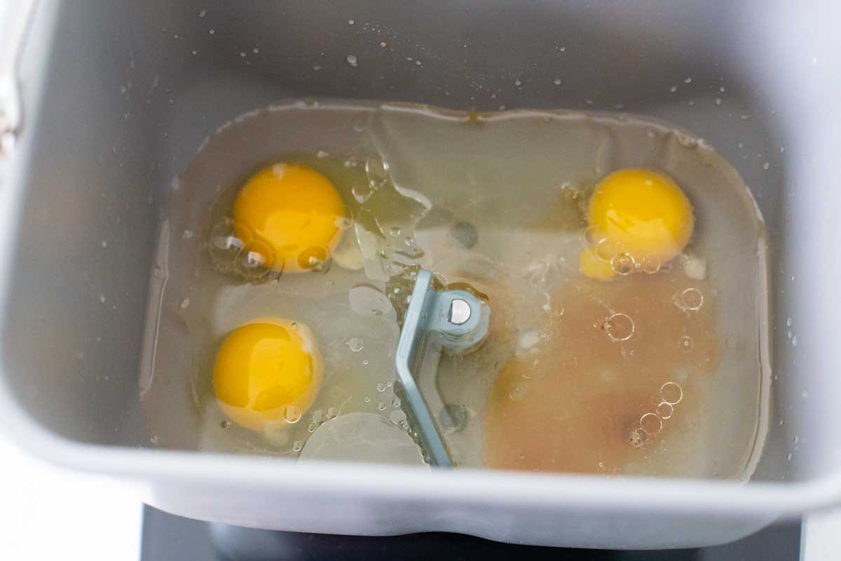 Eggs, water, oil, and honey are in the bread machine pan with the paddle attachment.