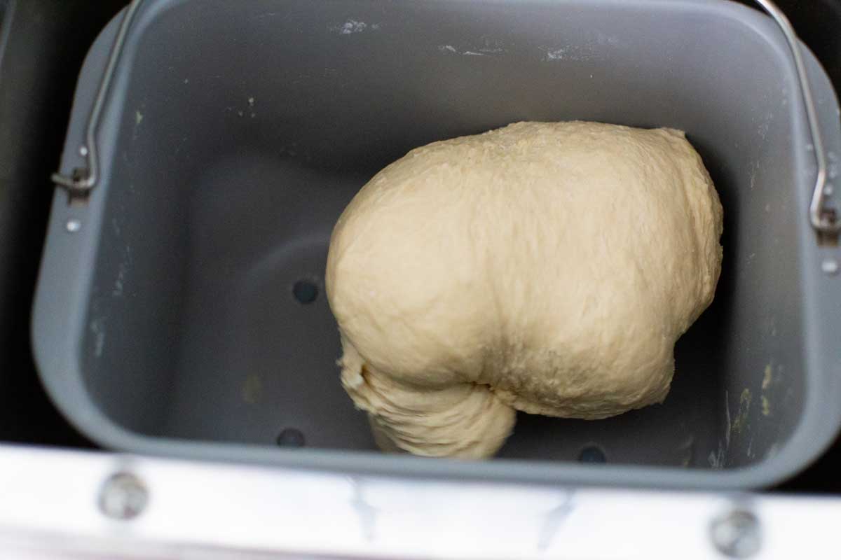 The dough is being kneaded by the bread machine and shows the proper smooth texture.