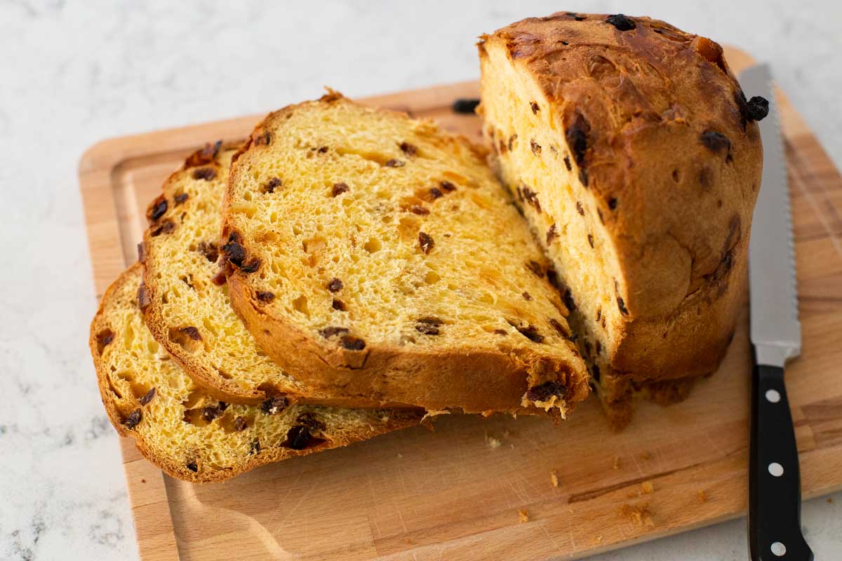 A sliced loaf of panettone shows the texture of the bread and the amount of dried fruits inside.