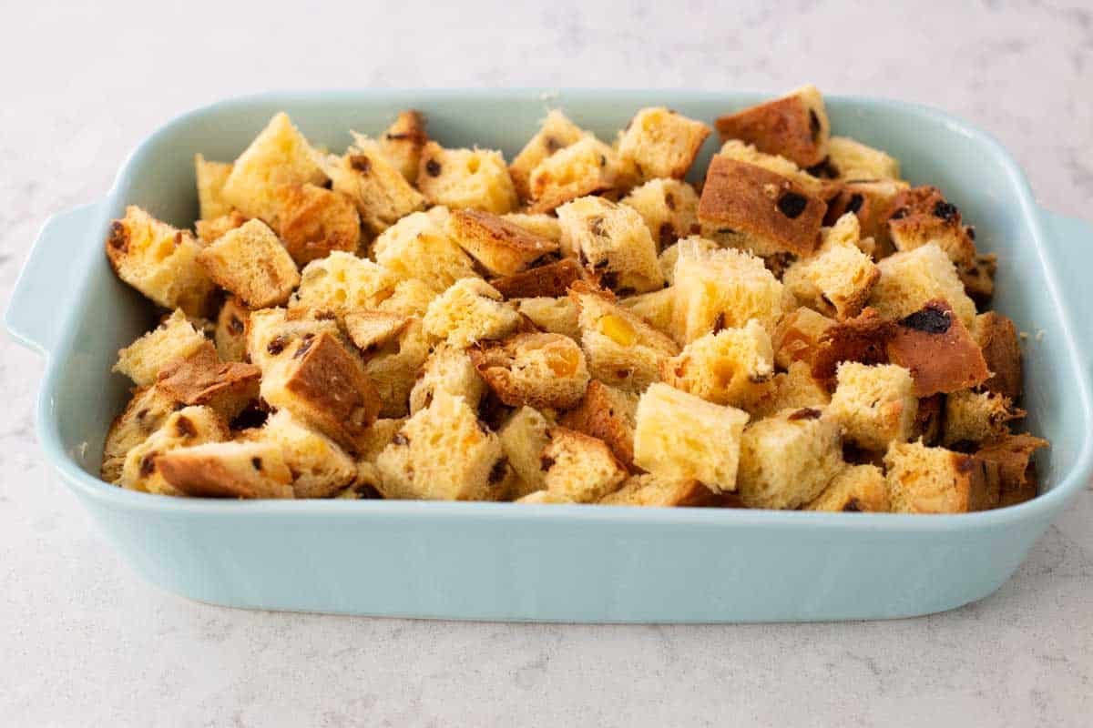 Butter the dish and cube the bread, scatter it evenly in the baking dish like this.