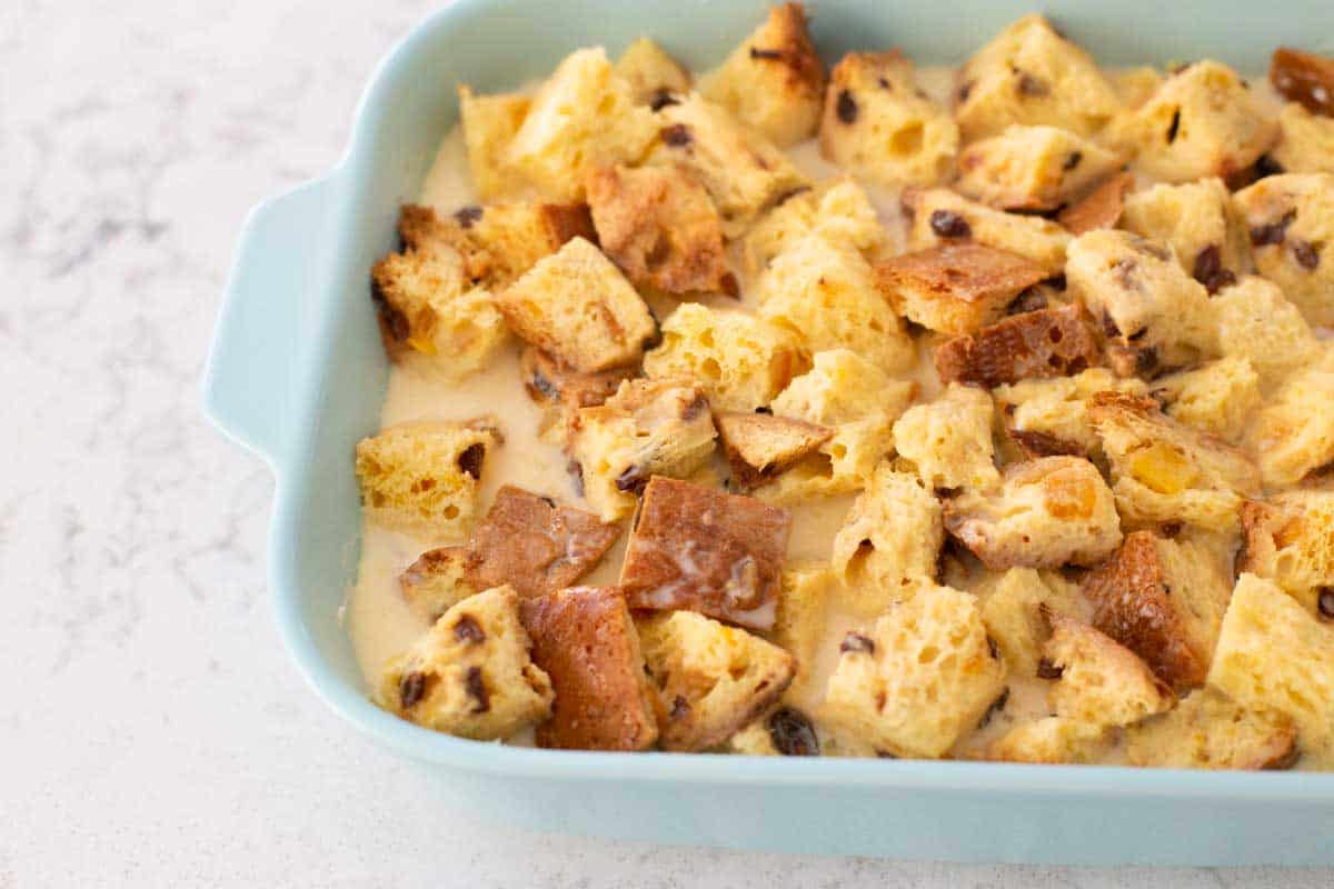 The custard mixture has been poured over the bread and the cubes are soaking up the liquid.