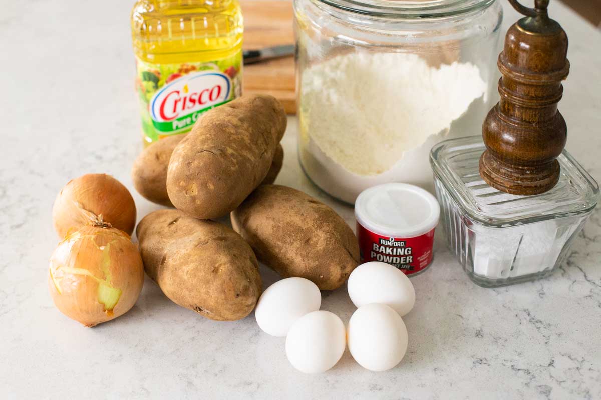The fresh potatoes and remaining ingredients to make homemade potato latkes are on the counter.