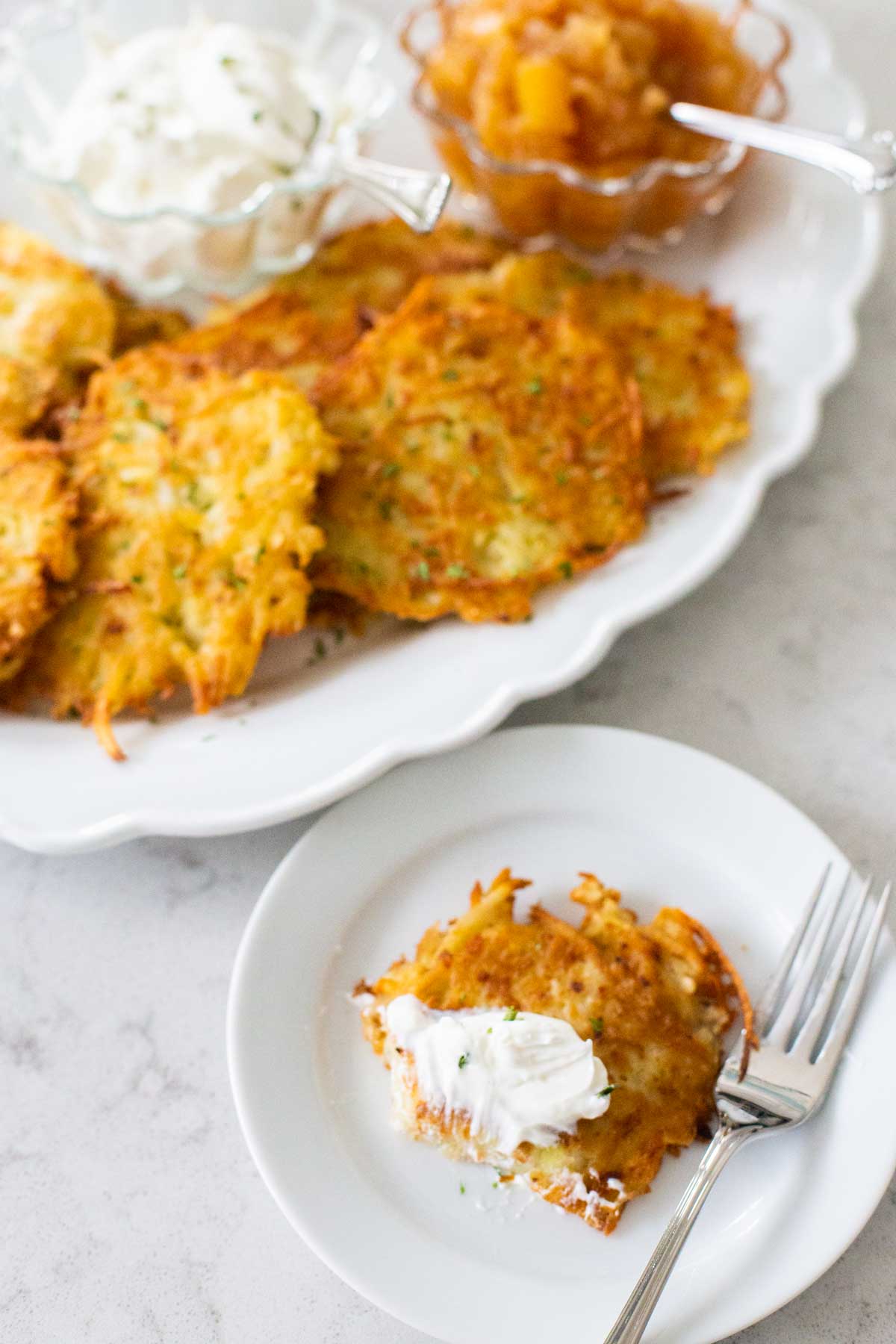 A serving of potato pancakes with sour cream and a fork.