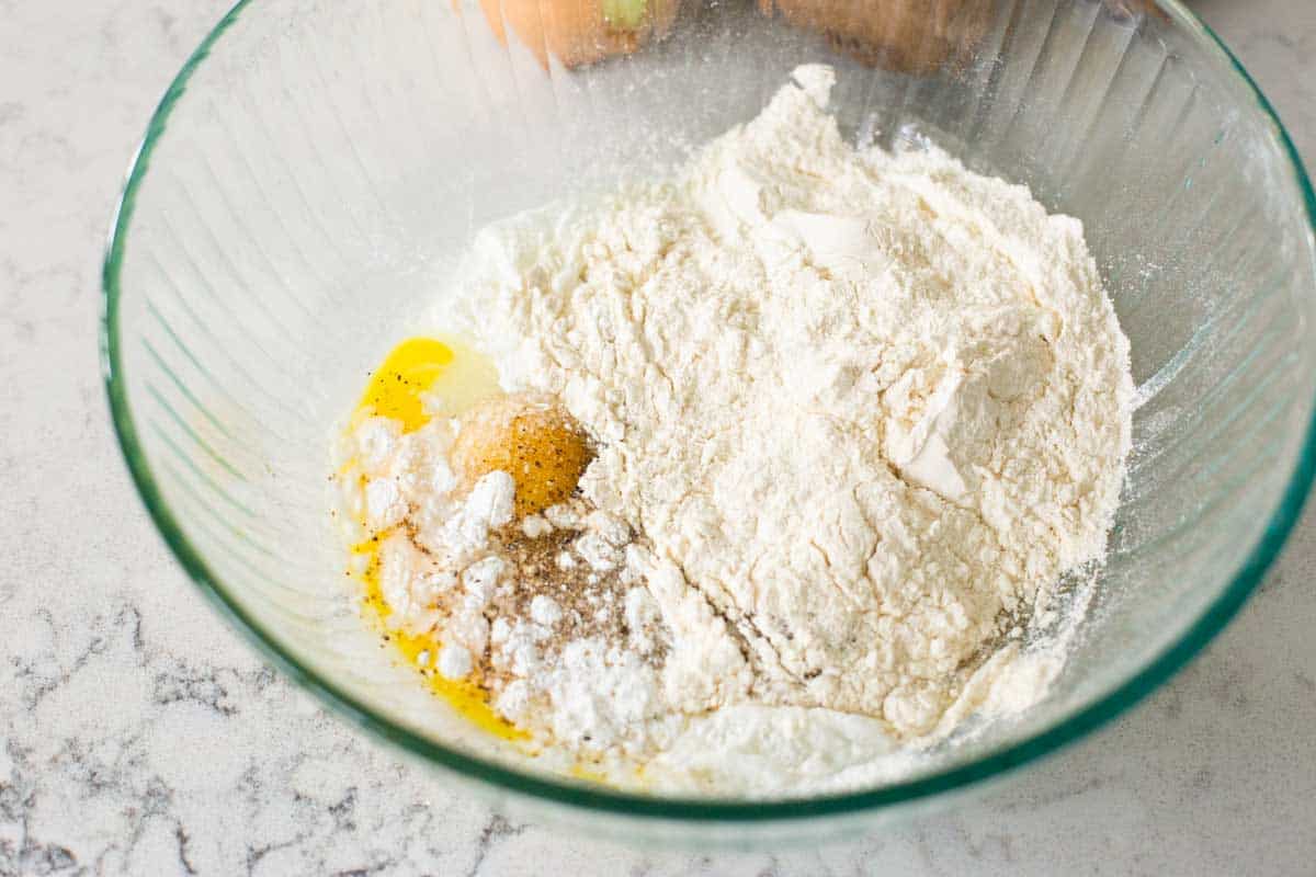 A large mixing bowl has eggs and flour for the latkes.