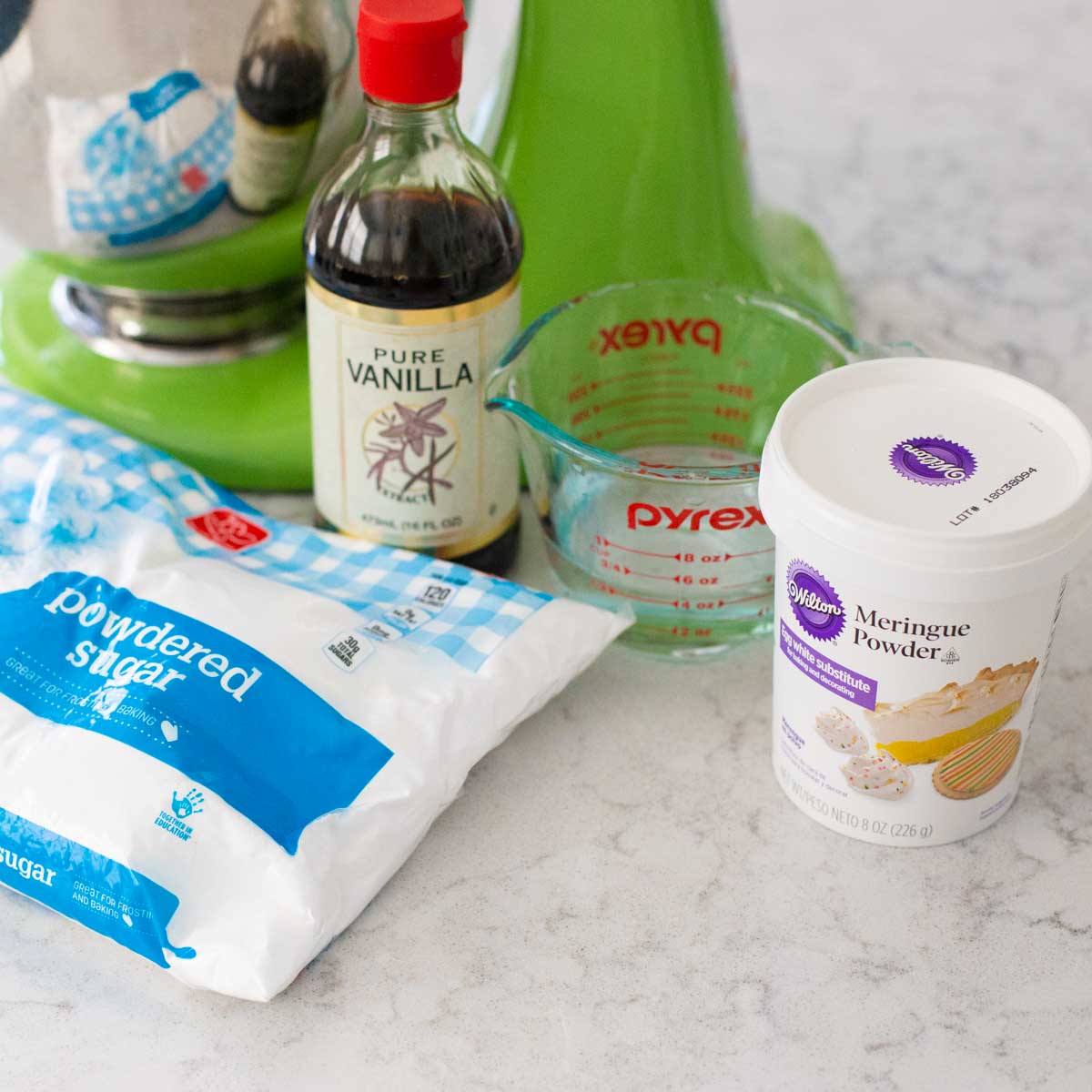 The simple ingredients to make royal icing for cookies are next to the stand mixer.