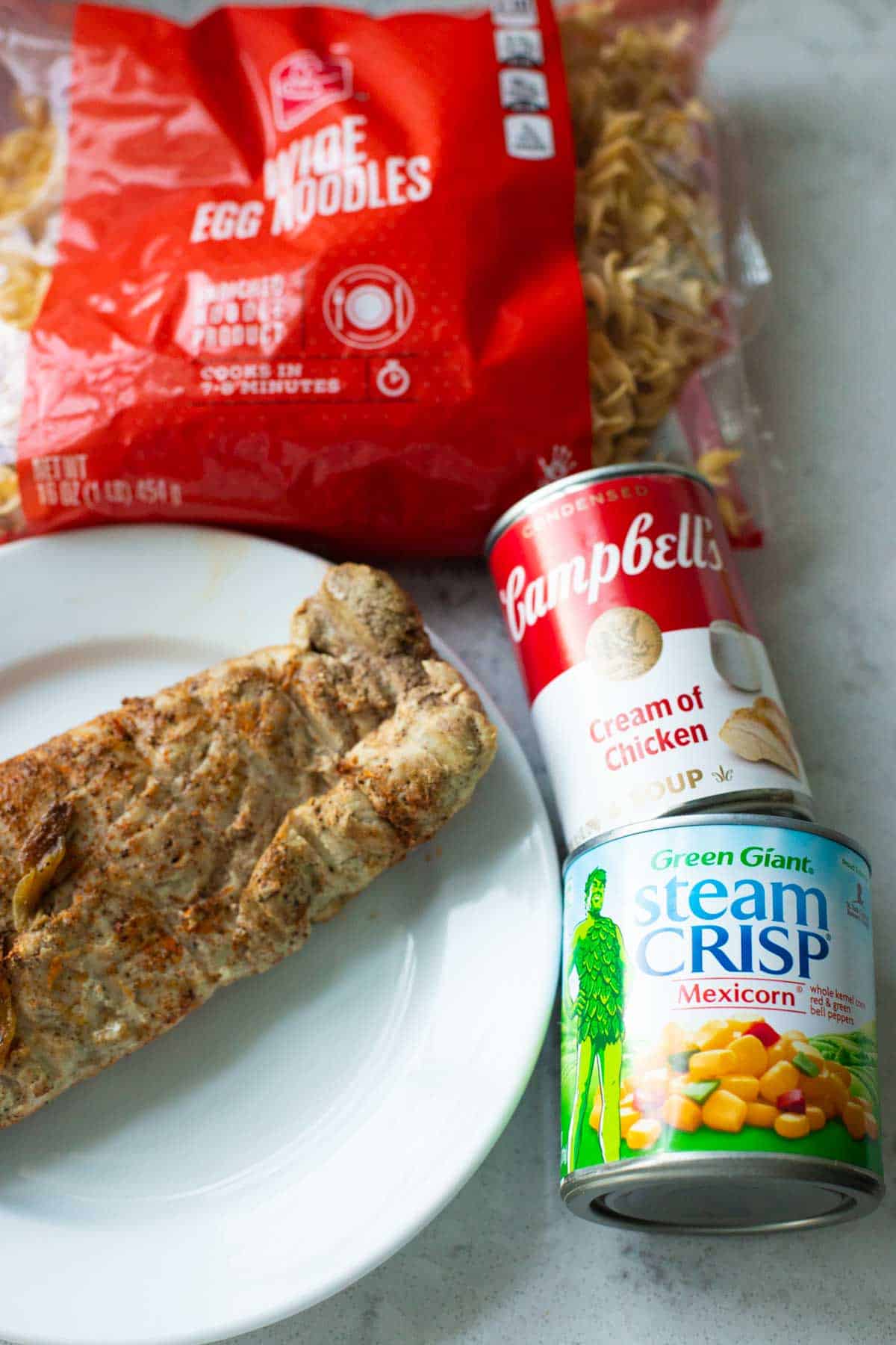 The leftover pork is on a dinner plate next to the remaining ingredients for the casserole.