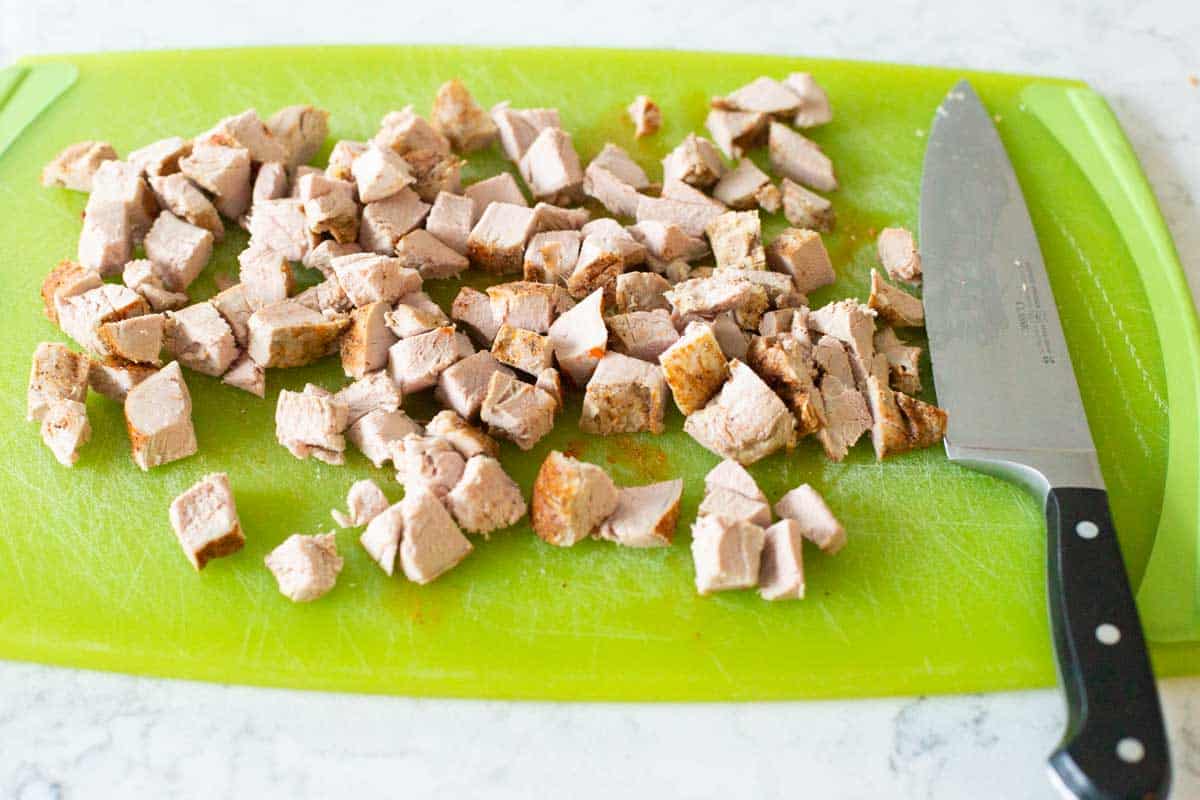 The pork tenderloin has been cut into bite-sized pieces with a chef knife.