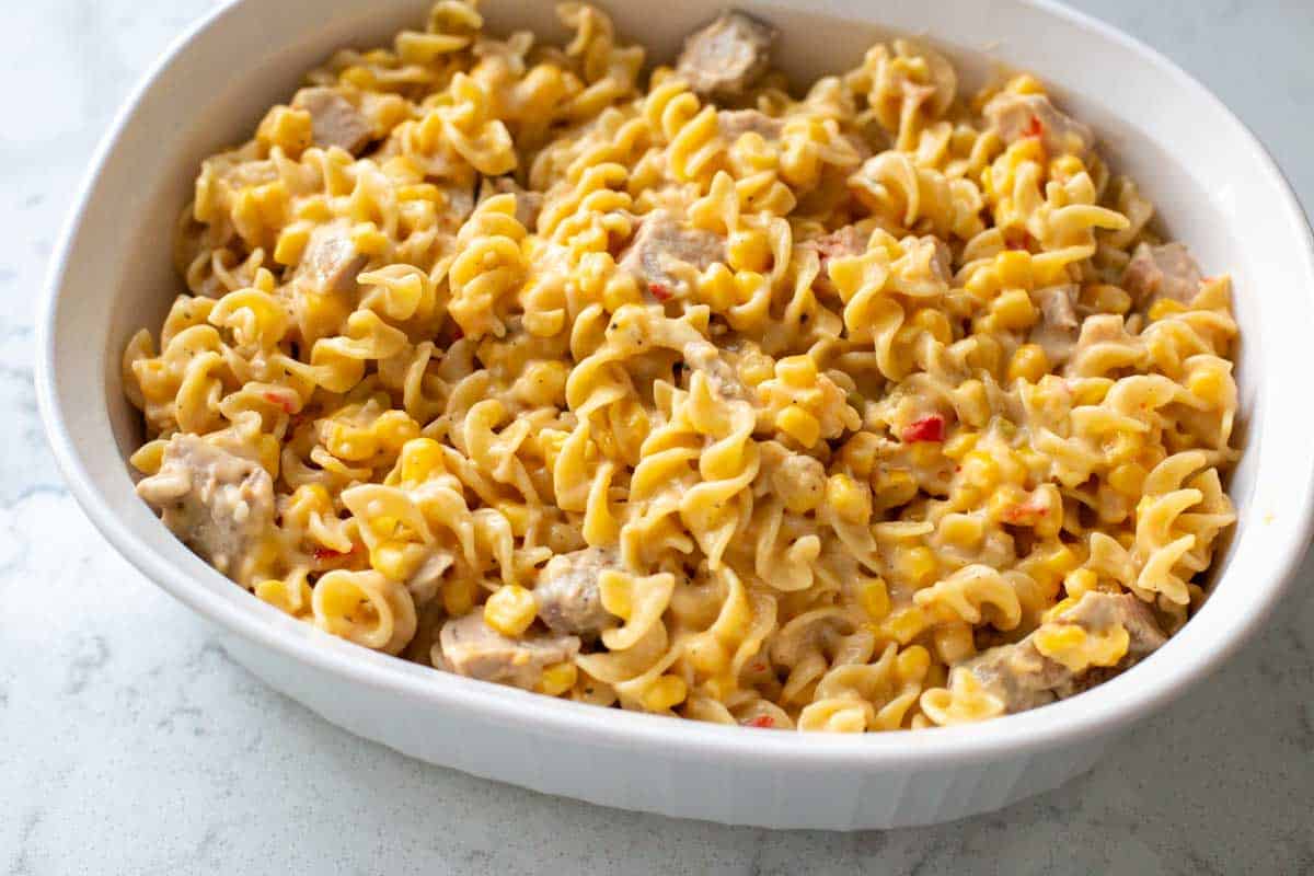 The pork casserole has been transferred to an oval shaped white casserole dish.