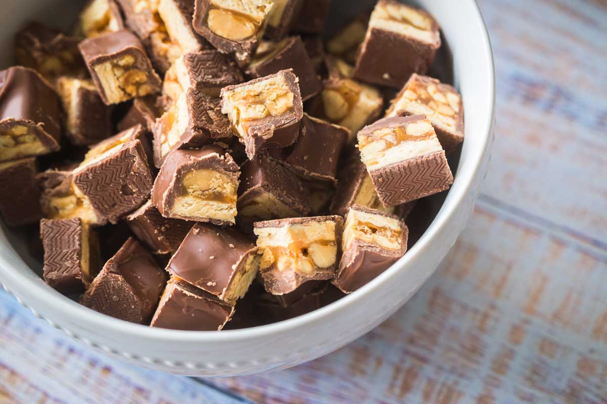 The Snickers candy bars have been chopped into bite-sized chunks and are in a white bowl.