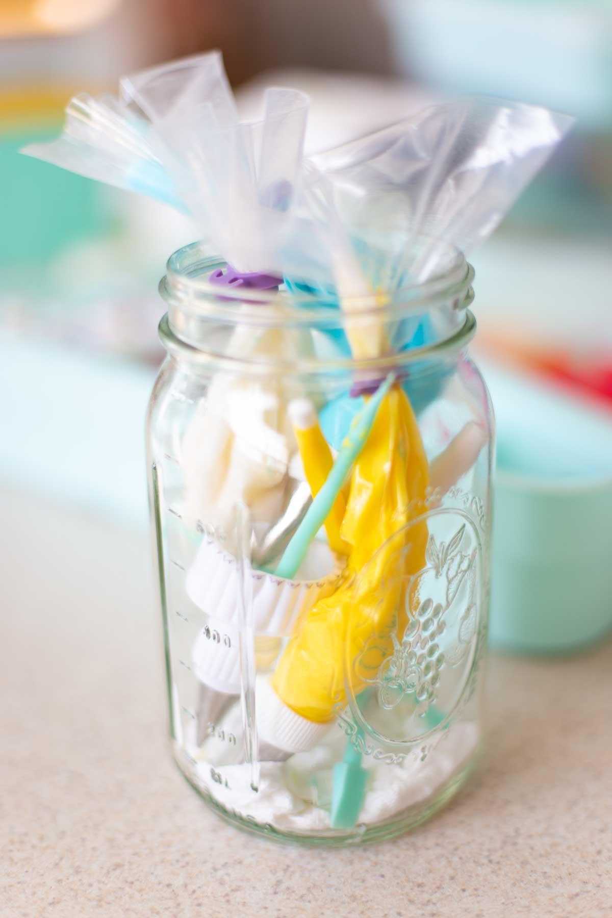 A jar filled with piping bags filled with icing ready to decorate cookies.