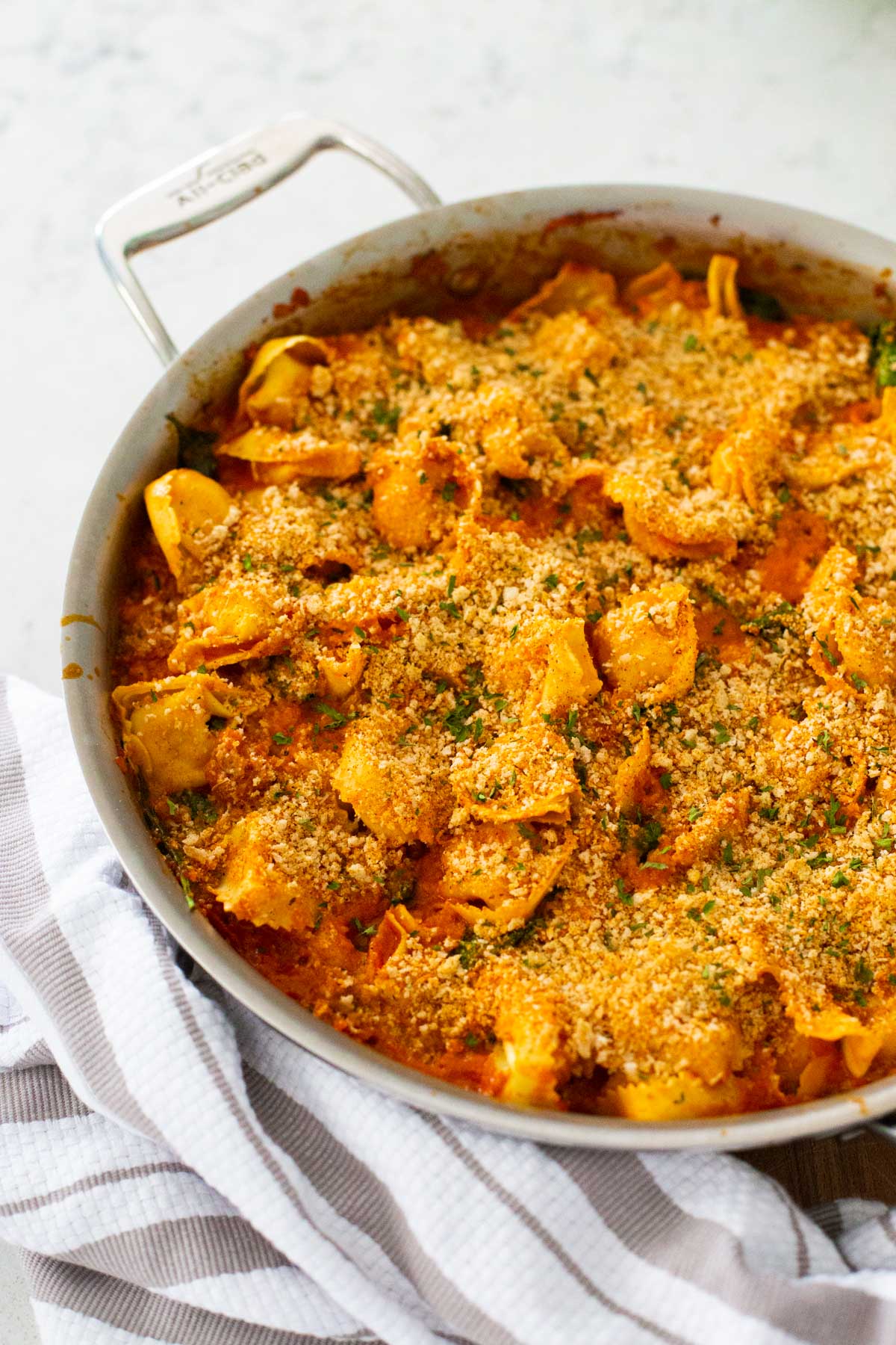The finished skillet filled with baked tortellini has crispy bread crumbs on top.