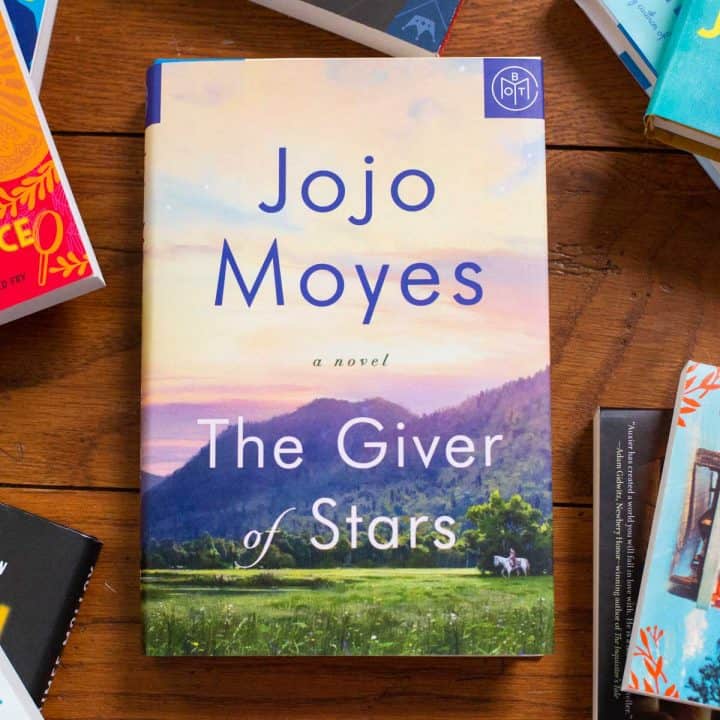 A copy of the book The Giver of Stars by Jojo Moyes sits on a table.