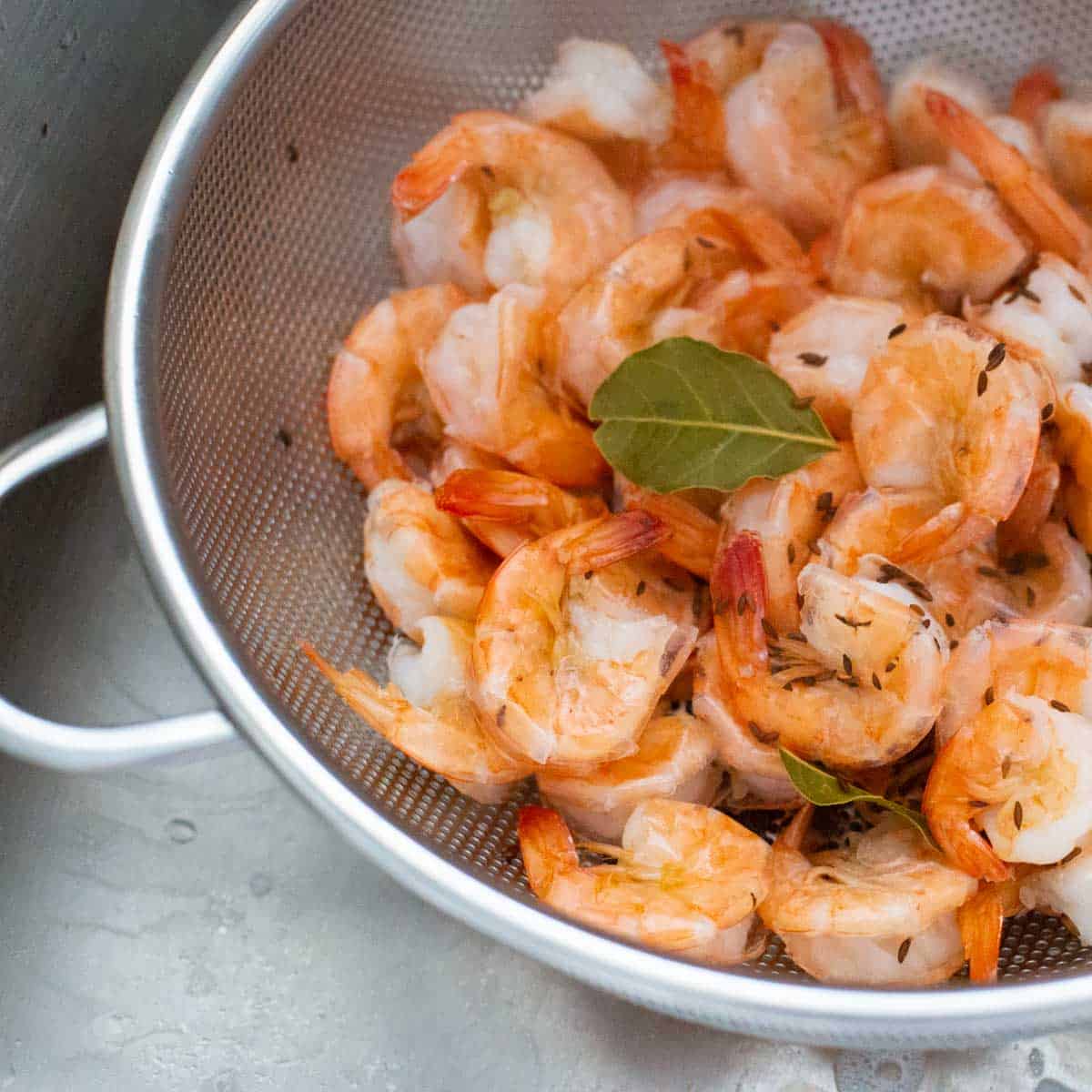 The shrimp have been strained into a colander in the kitchen sink.