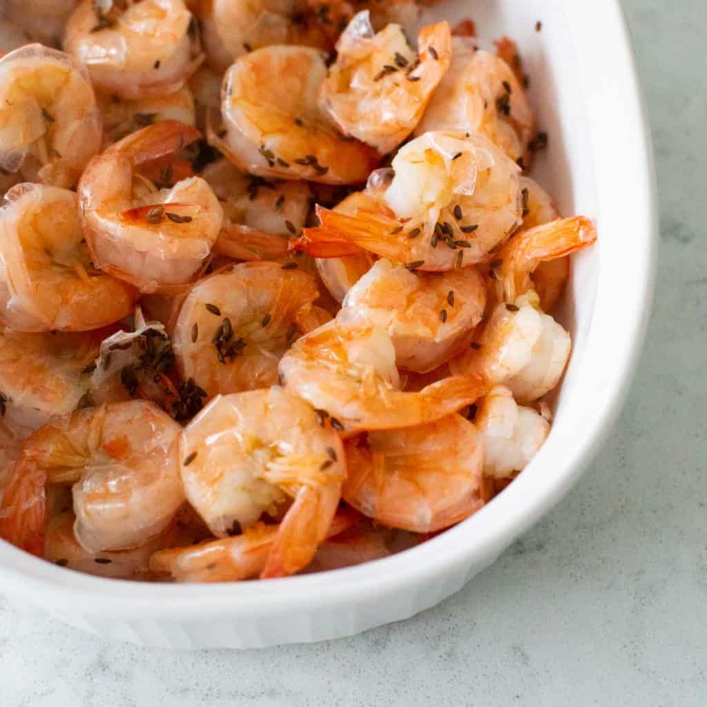 A serving dish filled with boiled shrimp with caraway seeds.