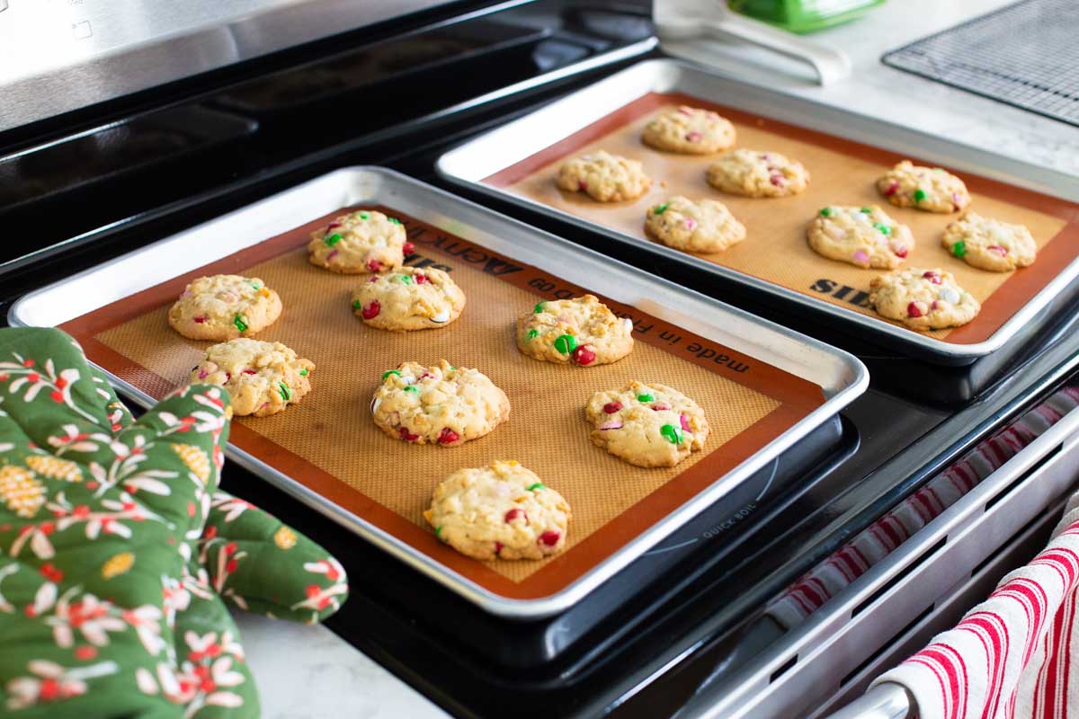 Two pans of cookies are cooling on the stovetop. 