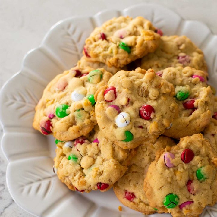 A plate of festive M&M cookies feature red, pink, green, and white candies for the holidays.