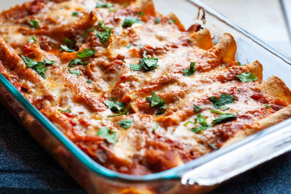 The baking pan has the finished chicken enchiladas.