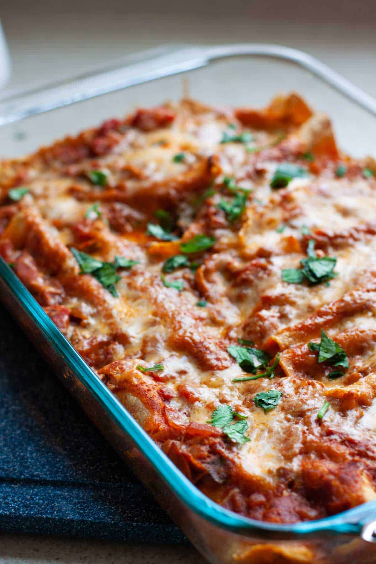 The baking pan has the finished chicken enchiladas.