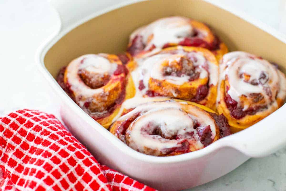 The rolls have been baked and spread with icing. 