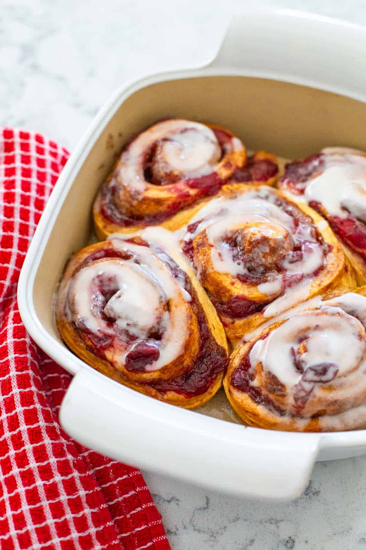 The rolls have been baked and spread with icing.