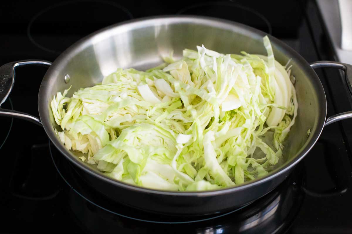 The sliced cabbage has been added to a large skillet.
