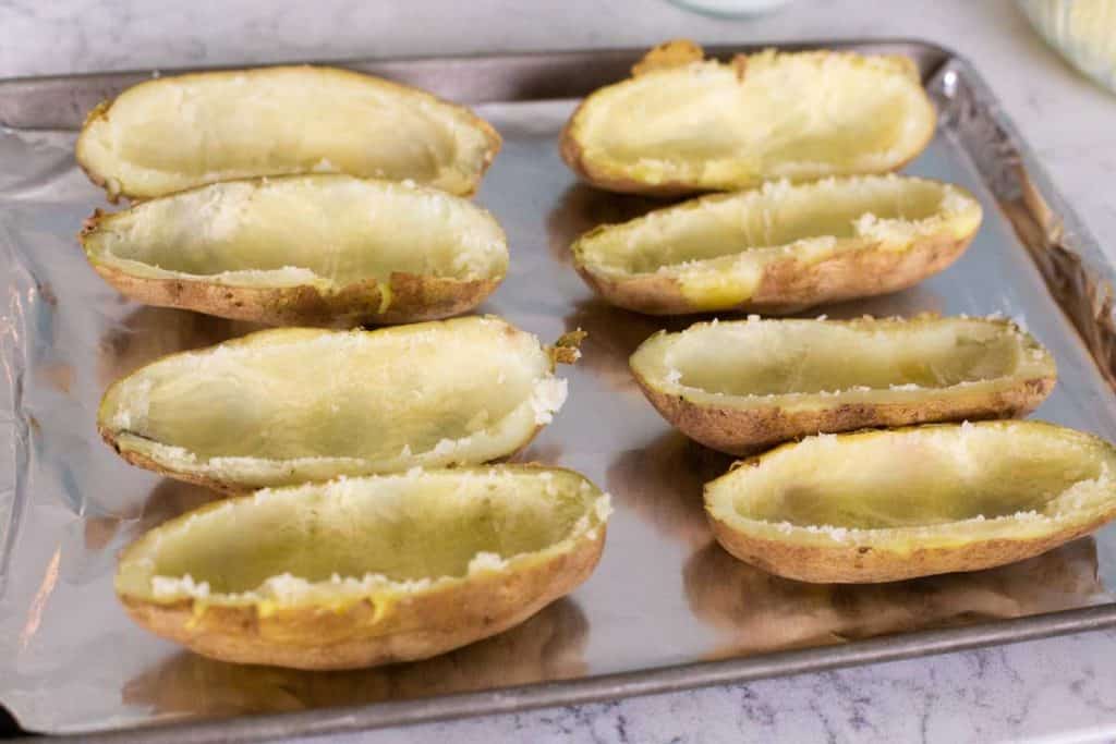 A baking sheet has 8 potato halves lined up for filling.