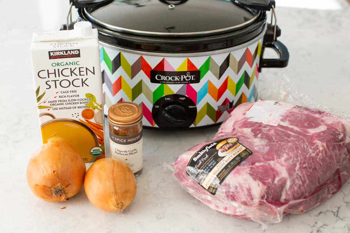 The ingredients to make pulled pork are in front of a slowcooker.