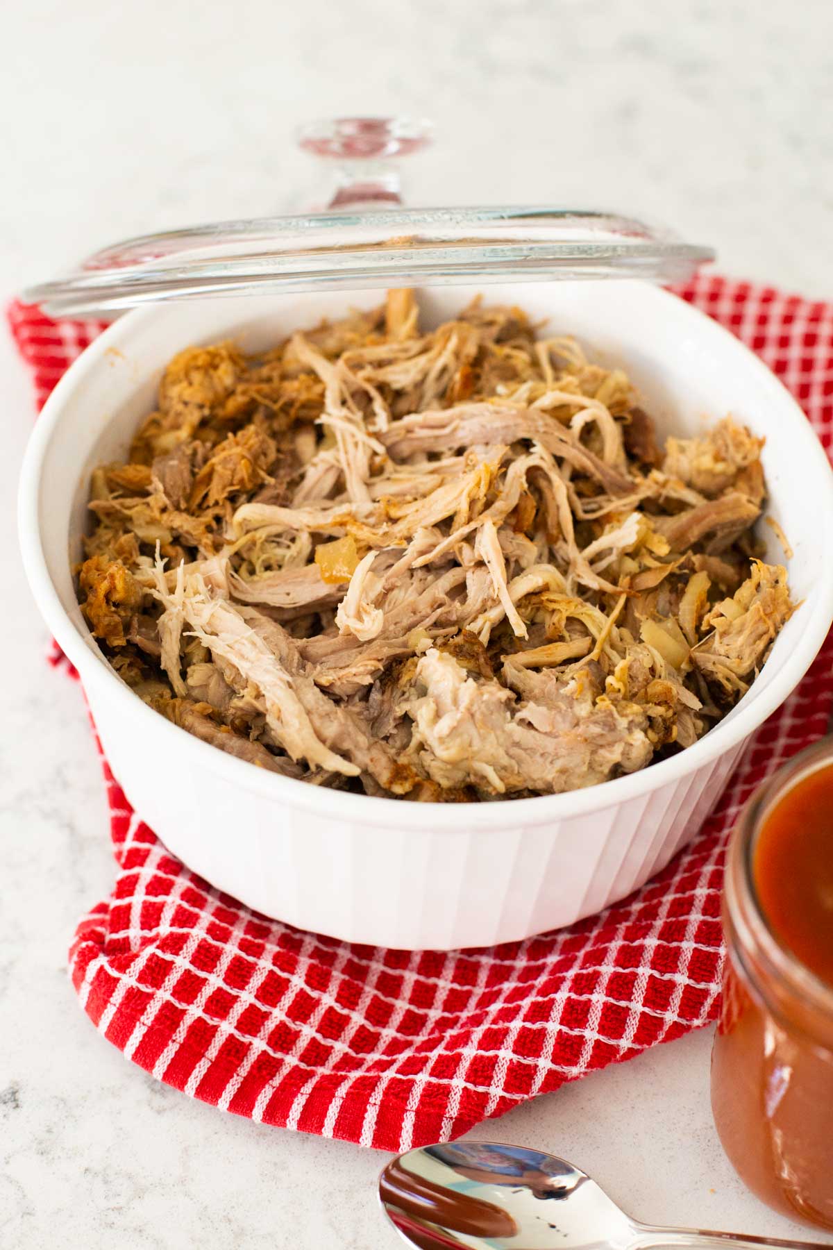 The cooked pork has been shredded and sits in a casserole dish.