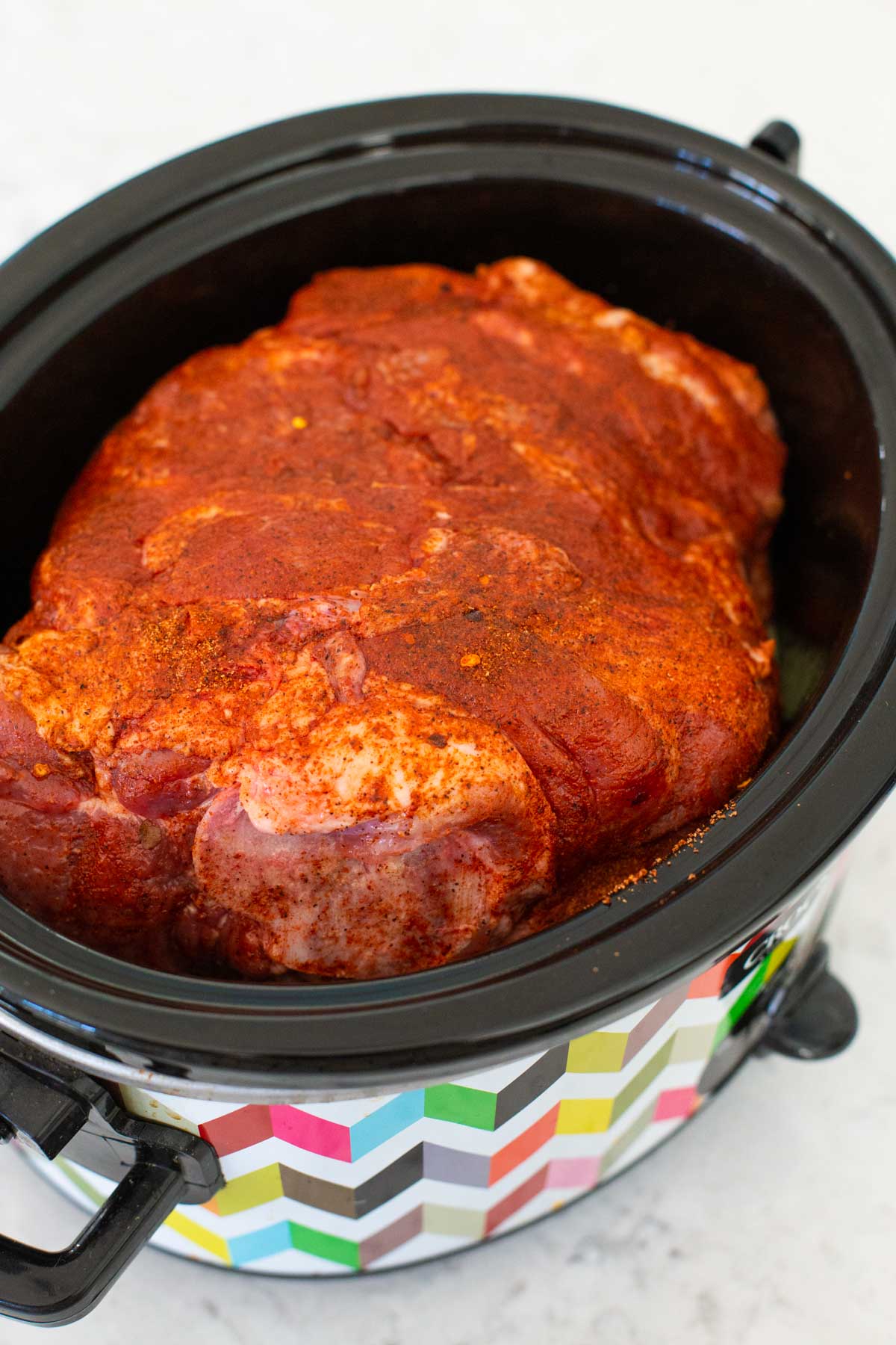 The pork roast has been placed inside the slowecooker for cooking.