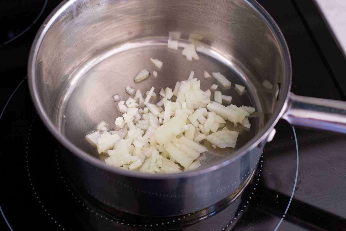 Chopped onions are being cooked in the sauce pan.