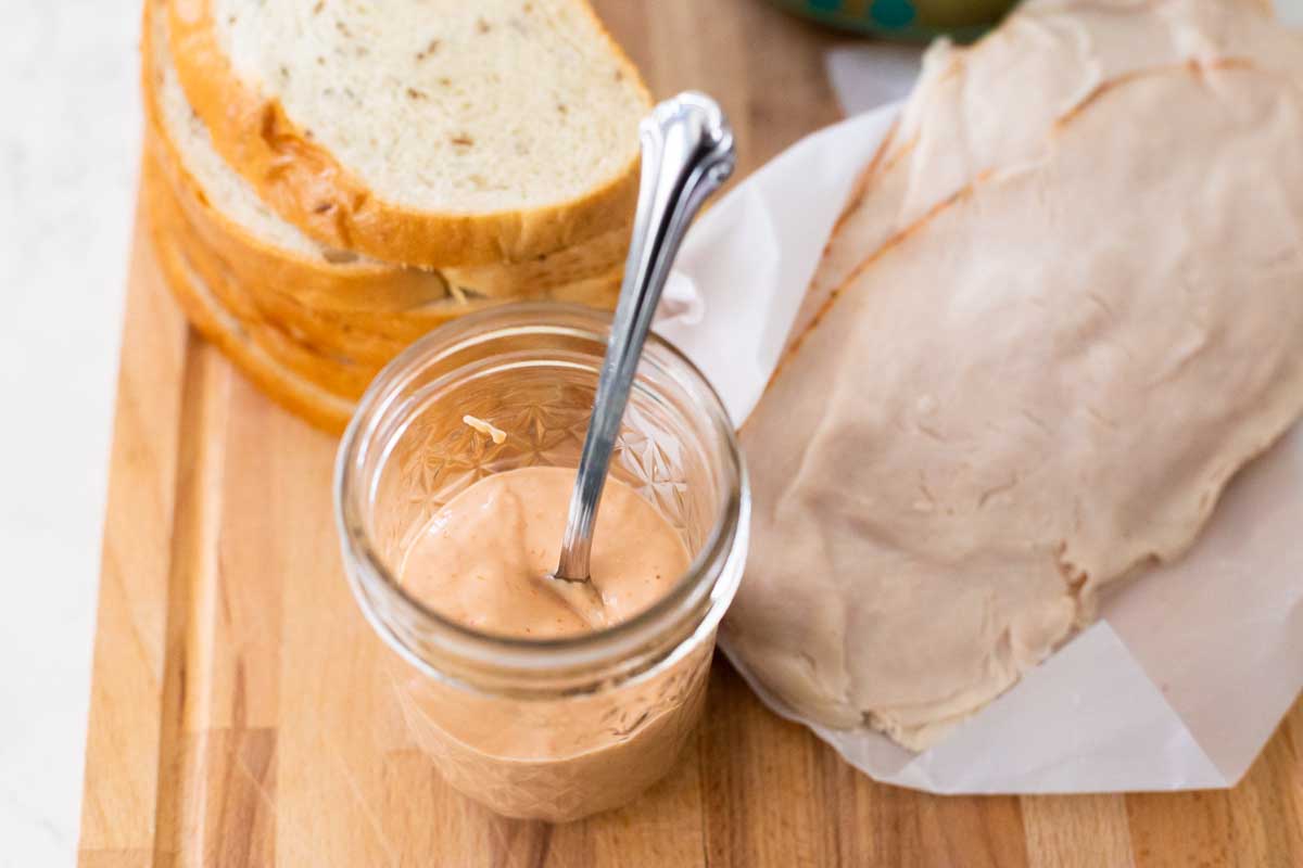 A sandwich board has a jar of spicy sauce in a mason jar.