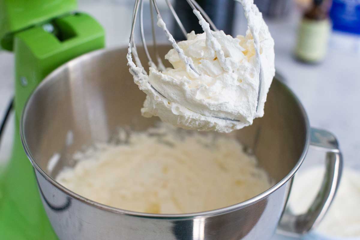 The whipped mascarpone filling is in a stand mixer with a whisk attachment.