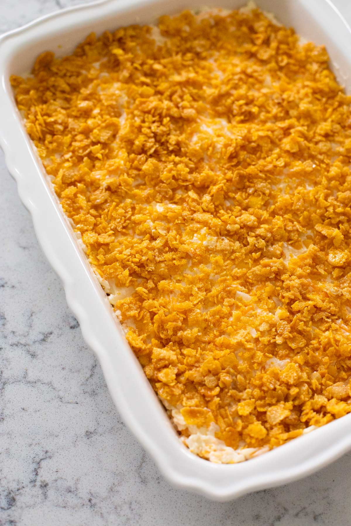 The potato casserole has been topped with cornflakes and baked in a 9 x 13 inch baking pan.