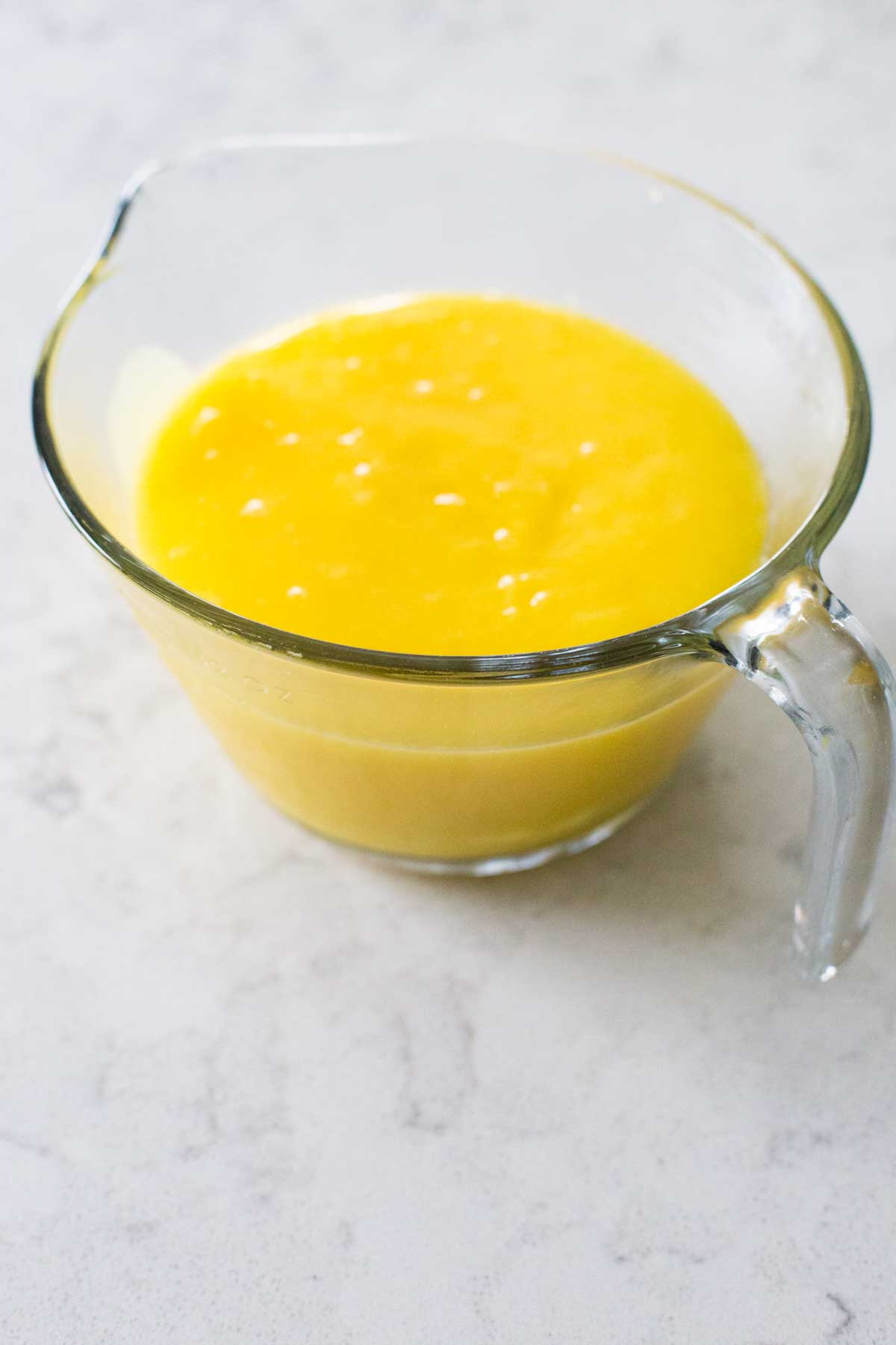 The finished lemon curd is in a large measuring cup.