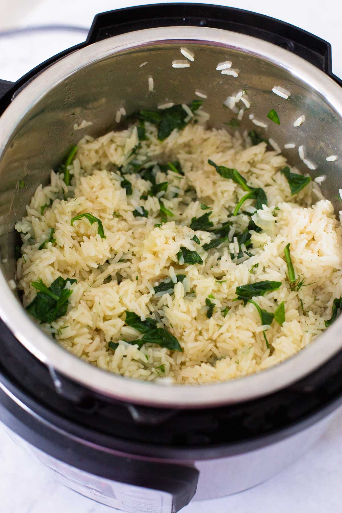 The spinach mixture has been stirred into the cooked rice inside the Instant Pot.