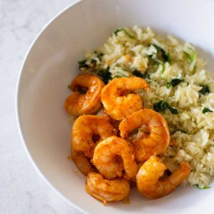 A bowl filled with white rice, spinach, and seasoned shrimp.