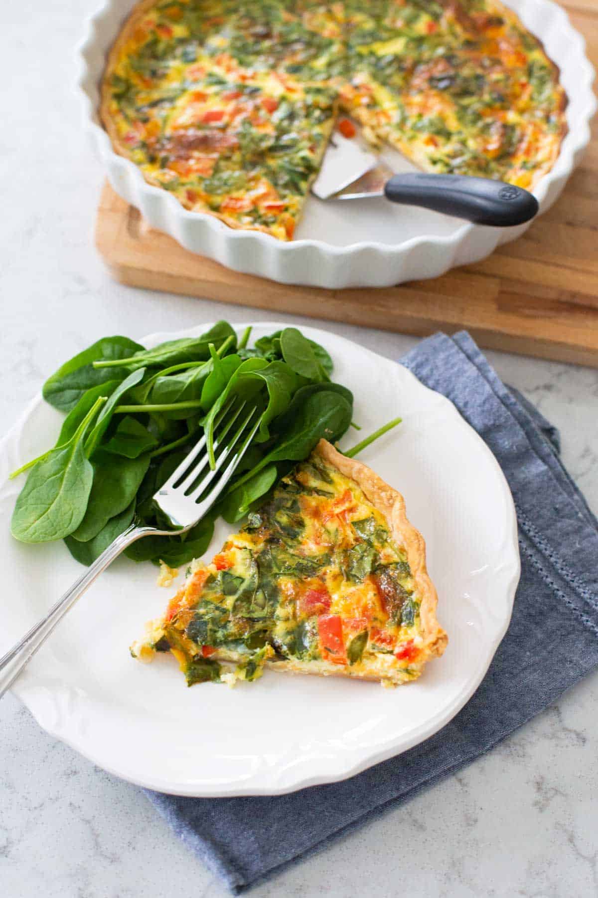 The quiche has been sliced and served on a plate with a side salad.