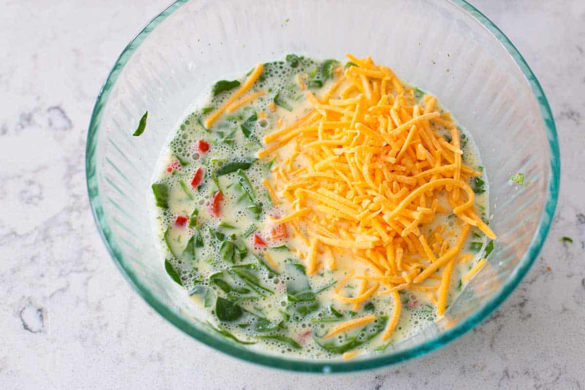 The eggs have been whisked with milk and the spinach and peppers and shredded cheese are about to be mixed in.