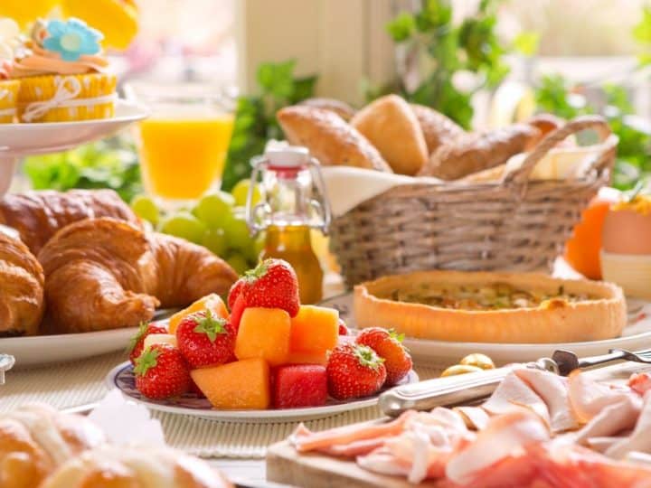 A home brunch table filled with breakfast items and fresh flowers.