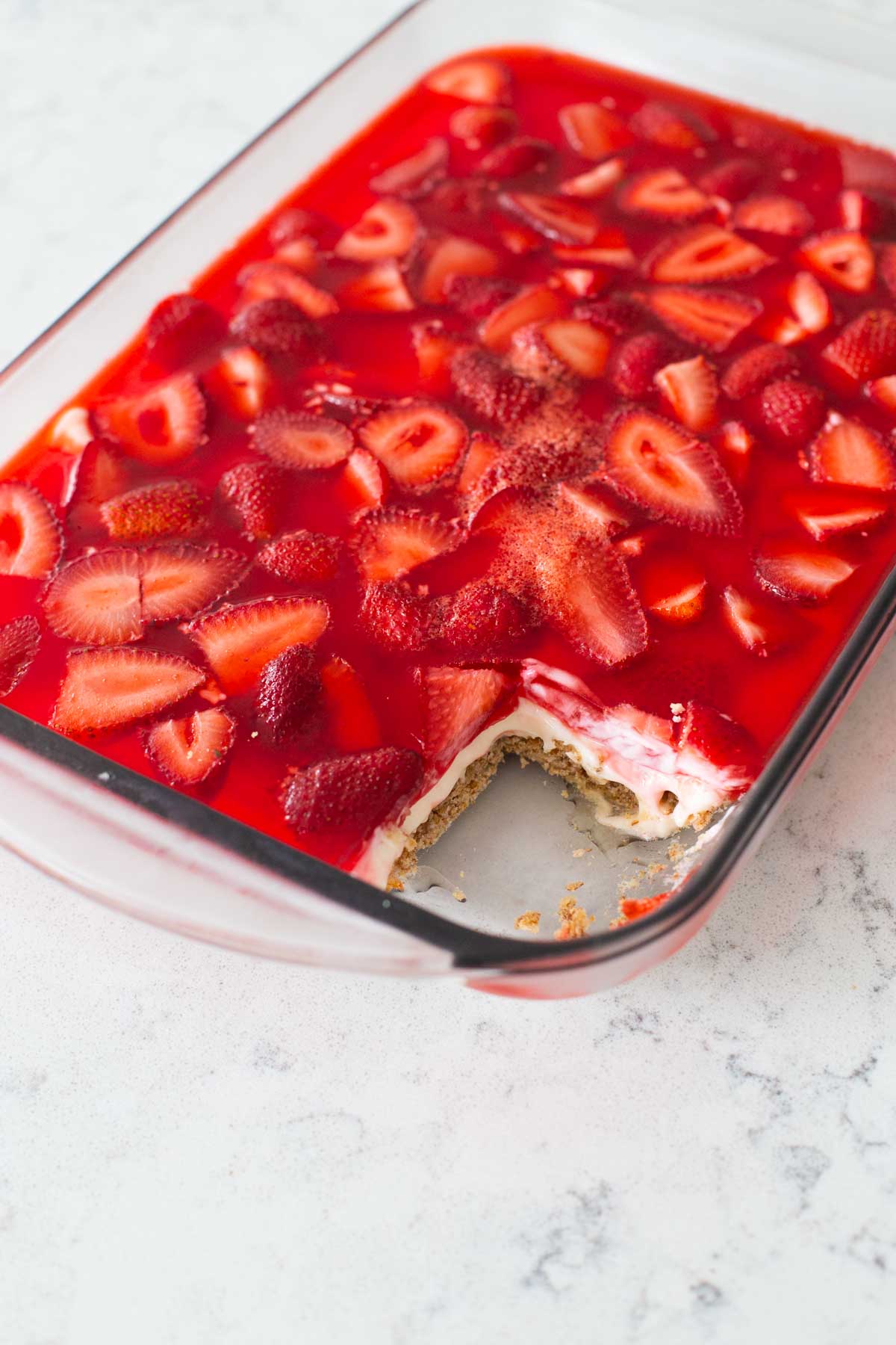 The 9x13-inch pan of strawberry pretzel salad has a slice missing.