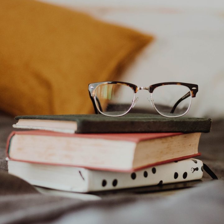 A stack of books and a pair of eye glasses.