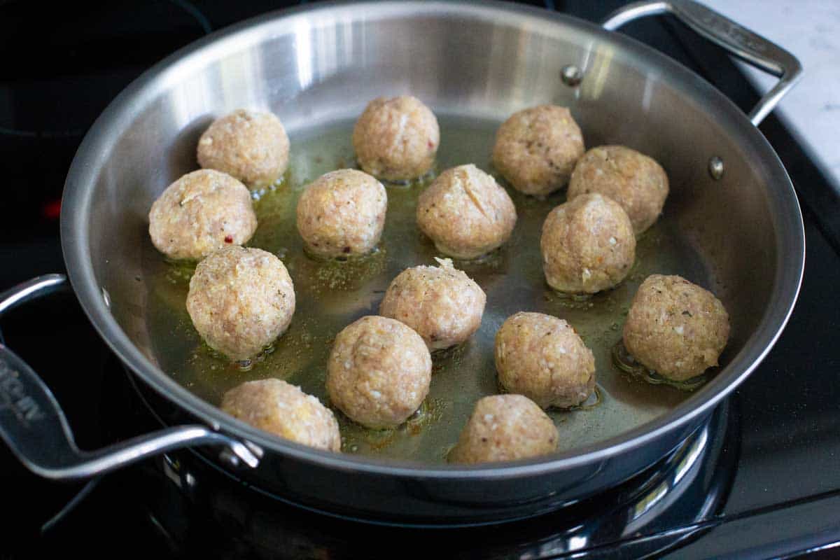 The chicken meatballs have been added to a hot skillet.