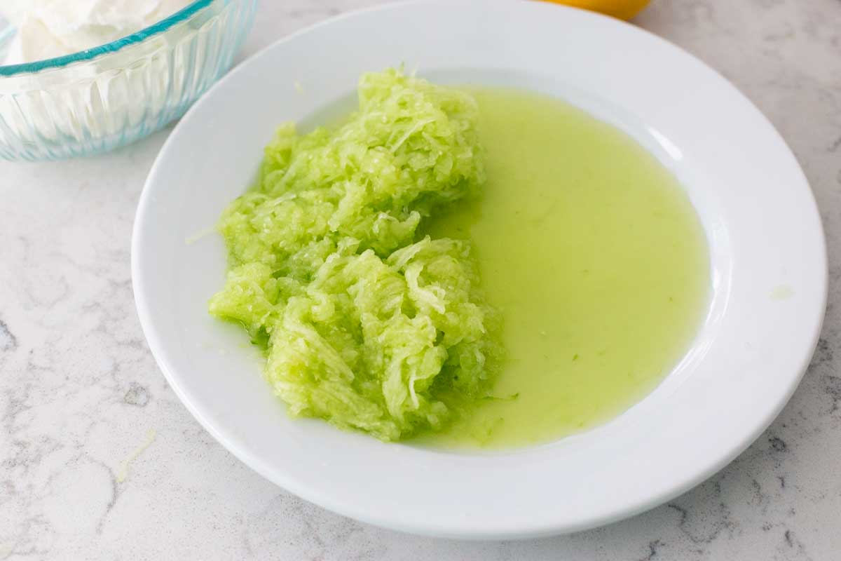 The grated cucumber has plenty of green liquid to be drained from the vegetable.