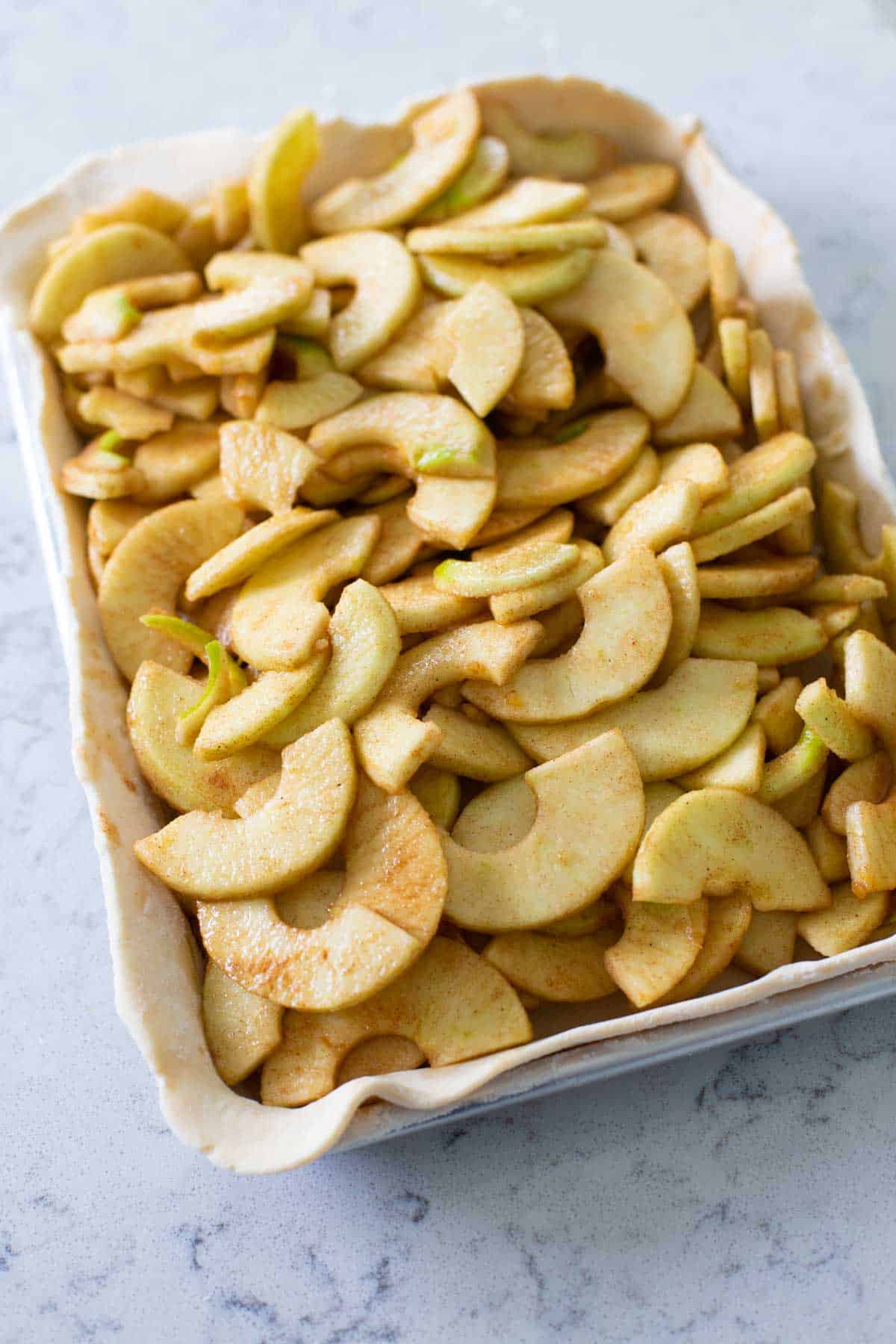 The bottom pie crust has been filled with sliced cinnamon apples.